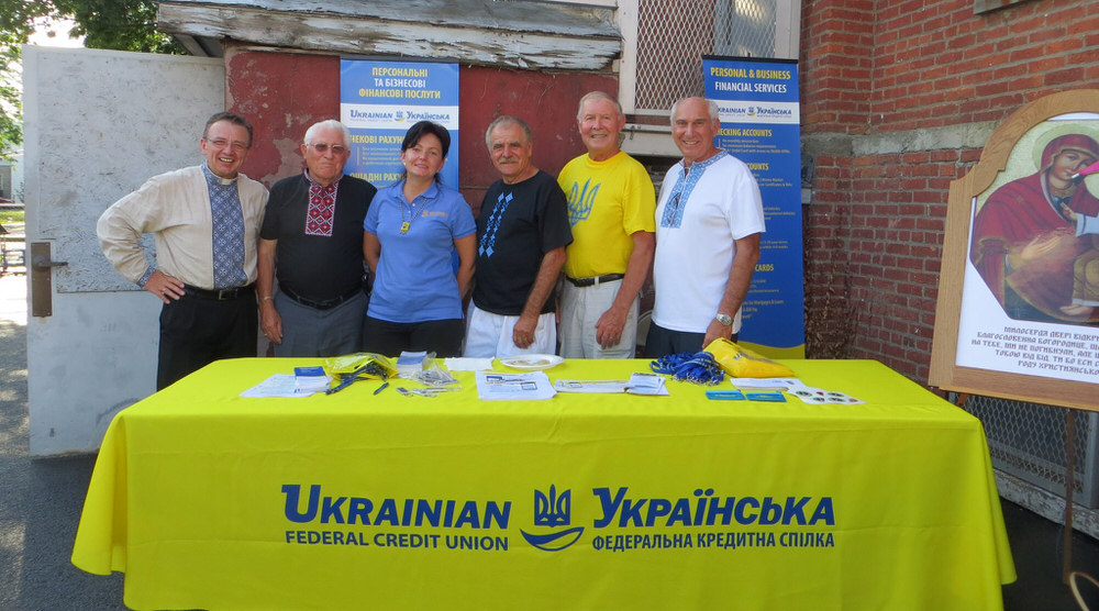 Community members stand with UFCU staff by booth