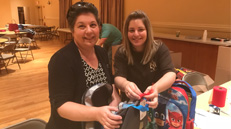 Local youth organization volunteers smile as they prepare donation of backpacks