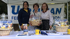 Three women posing for photo behind a booth