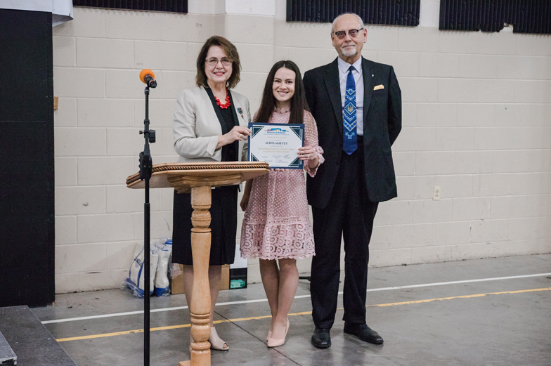 three adults standing, one receives certificate