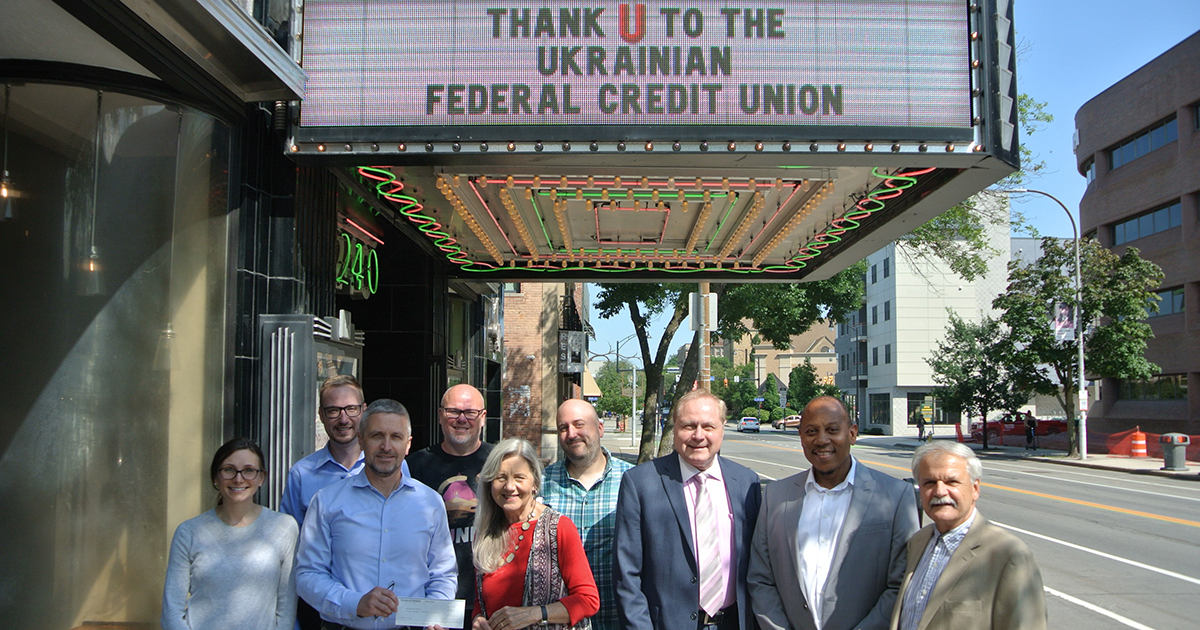 Group of adults standing, smiling under marquee