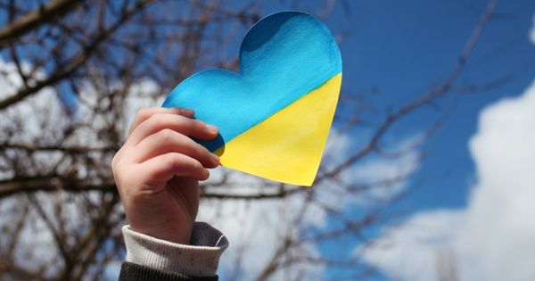 A hand with a paper yellow-blue heart