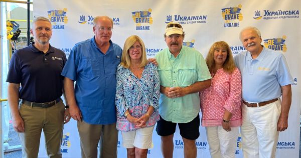 UFCU team with members near banner